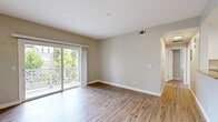 Located at 2075 Funny Cide Stn in Napa, CA, this two-bedroom residence offers a thoughtfully designed single-floor layout with a clean, neutral aesthetic throughout. Light wood-style flooring runs continuously across the living areas, complementing the soft gray-beige wall tones and crisp white trim.

The combined kitchen and living room forms the heart of the home. The kitchen is well-appointed with white shaker-style cabinetry, granite-look countertops, a full suite of stainless steel appliances including a refrigerator, range, microwave, and dishwasher, and a skylight panel that brightens the workspace. A chandelier anchors the dining area nearby. The living room opens directly to a private balcony through wide sliding glass doors, offering views of mature greenery and filling the space with natural light.

The spacious primary bedroom includes direct access to a bathroom with white vanity cabinetry and a dedicated closet. The second bedroom is comfortable in scale and features a ceiling fan and a window overlooking outdoor greenery. A hallway connects the bedrooms and provides additional closet storage. The entry features a classic paneled front door with flush ceiling lighting. Throughout the home, the design is consistent, clean, and move-in ready.