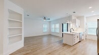 This well-designed single-floor residence offers 3 bedrooms, 3 bathrooms, and a thoughtfully planned open-concept layout that maximizes functionality and flow. Light hardwood-style flooring runs throughout the entire home, creating a cohesive, airy aesthetic complemented by crisp white walls and abundant natural light from multiple windows dressed with white horizontal blinds.

The combined kitchen and living area forms the heart of the home. The kitchen features a central island with a white quartz countertop, an undermount sink with a matte black faucet, white shaker cabinetry, stainless steel appliances, and elegant pendant lighting. The adjoining living room is generously proportioned, with a ceiling fan and built-in shelving that adds both style and practical storage.

Each of the three bedrooms is well-lit, benefiting from large windows and ceiling fans. The primary bedroom offers a comfortable footprint with direct access to a dedicated closet. All three closets are outfitted with white wire shelving systems, providing organized storage solutions.

The bathrooms maintain the home's clean, modern aesthetic, featuring white tile surrounds, soaking tubs, and matte black fixtures that add a sharp design contrast. Overall, this residence presents a bright, contemporary living environment with consistent finishes throughout.