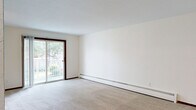 Located at 2021 Edgerton St in Maplewood, MN, this single-floor residence offers two bedrooms and two bathrooms within a well-organized layout. The living room is bright and open, featuring plush carpeting, a baseboard heating system, and a sliding glass door that leads to a private balcony overlooking a lush, tree-lined outdoor setting. The adjacent dining area flows naturally from the living space, enhancing the open feel of the common areas. The kitchen is equipped with rich, dark wood cabinetry, light stone-toned countertops, a double-basin stainless steel sink, and wood-style flooring, providing a functional and warm cooking environment. Both bedrooms are comfortably sized and carpeted, each featuring louvered bi-fold closet doors offering generous storage capacity. The primary bedroom provides a notably spacious footprint. The two bathrooms are finished with classic white tile flooring, wood vanities with light countertops, and full tub-shower combinations with grab bar fixtures. A hallway connects the private quarters, and the unit benefits from an impressive total of five closets throughout, ensuring abundant storage. The neutral color palette and clean finishes give the space a bright, move-in-ready character.