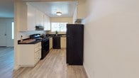 Located at 1539 Tavern Road, Unit 23 in Alpine, California, this single-story residence offers a practical and comfortable layout with thoughtfully appointed spaces throughout. The open living area features light wood-look flooring, neutral walls, a textured ceiling, and a window that allows natural light to brighten the room. A wall-mounted HVAC unit provides convenient climate control. The living space flows directly into the kitchen, which is equipped with white cabinetry, dark granite-style countertops, black appliances including a refrigerator, electric range, and dishwasher, as well as a window above the sink that adds additional natural light. The bedrooms are carpeted in warm neutral tones, each featuring windows with blinds for natural light and privacy. One bedroom includes mirrored sliding closet doors, offering both storage and a sense of added space. The bathroom is well-appointed with white cabinetry, a dark speckled countertop, an undermount sink with brushed nickel fixtures, and a large mirror above the vanity. A shower with a curtain rod is accessible from the bathroom. Throughout the unit, the consistent use of neutral tones and wood-look flooring in common areas creates a cohesive, clean aesthetic that is both functional and move-in ready.