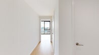 This contemporary high-rise unit offers 2 bedrooms and 1 bathroom across a single floor, thoughtfully designed with clean lines and modern industrial aesthetics. Exposed concrete ceilings contrast beautifully with crisp white walls and light hardwood flooring found throughout, creating a refined urban atmosphere.

The open-plan living area and kitchen are bathed in natural light from expansive floor-to-ceiling windows framed in matte black, offering breathtaking panoramic views of the downtown skyline. The kitchen features light wood cabinetry, stainless steel appliances including a refrigerator, range, and dishwasher, complemented by track lighting mounted on the concrete ceiling.

The spacious primary bedroom is a standout feature, wrapped in floor-to-ceiling glass on two sides, delivering dramatic corner city views. The second bedroom also benefits from large windows with elevated outlooks. A hallway connects the bedrooms to the shared bathroom and closet, while a dedicated entrance provides a welcoming transition into the home.

The unit also includes access to an outdoor balcony showcasing sweeping high-rise views of the surrounding urban landscape. Throughout the space, the interplay of natural light, industrial materials, and city vistas creates a compelling and sophisticated living environment.