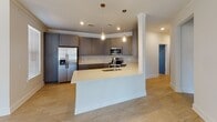 This single-floor residence offers a thoughtfully designed layout with modern finishes and a cohesive neutral color palette. The open-concept kitchen serves as the heart of the home, showcasing gray shaker-style cabinetry, a tasteful tile backsplash, stainless steel appliances, and a large peninsula island with a quartz countertop and undermount sink. Pendant lighting adds warmth above the island, while recessed lighting illuminates the space throughout. Light wood-look flooring extends seamlessly through the main living and kitchen areas, creating a bright, airy atmosphere. A dining area adjacent to the kitchen features multiple windows and a glass-panel door providing access to the exterior. The bedrooms are carpeted for comfort, each outfitted with a ceiling fan and generous windows that invite abundant natural light and views of the surrounding neighborhood. Several bedrooms include dedicated closets, with the primary suite offering a walk-in closet with wire shelving. The primary bathroom features a dark-toned vanity with quartz countertops and a large mirror. A secondary bathroom includes a matching vanity and clean, minimalist fixtures. Crown molding accents the main living spaces, adding a refined architectural detail throughout this move-in-ready home.