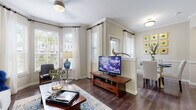 This thoughtfully designed single-floor residence offers a seamless blend of comfort and style across its open-concept layout. Rich, dark hardwood flooring flows through the main living areas, complemented by crisp crown molding and neutral warm-toned walls that create a bright, welcoming atmosphere throughout.

The living room is a standout space, anchored by a bay window that floods the room with natural light through sheer white curtains and plantation shutters. Crown molding adds architectural elegance, while a ceiling fan and ample room for furnishings make it both functional and inviting.

The dining area connects naturally to the living space, featuring a glass-top dining table, wainscoting details, and a window that brings in additional natural light. Adjacent to the dining room, the kitchen is equipped with dark espresso cabinetry, granite countertops, stainless steel appliances, and a breakfast bar — ideal for casual dining or entertaining. A built-in desk nook provides a convenient workspace.

The bedroom offers plush carpeting, generous natural light, and a mirrored decorative headboard feature that adds a striking focal point. The bathroom is finished with granite countertops, dark wood cabinetry, marble-style tile flooring, and a full soaking tub with shower.

Completing the home is a dedicated in-unit laundry room with full-size washer and dryer, tile flooring, and additional storage cabinetry.