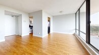 Located at 80 Mooregate Crescent in Kitchener, Ontario, this one-bedroom, two-bathroom unit offers a well-organized layout filled with natural light. The open living area is anchored by warm hardwood flooring and a sweeping wall of floor-to-ceiling windows that frame expansive views of the city skyline and surrounding greenery. A set of sliding doors leads to a spacious balcony enclosed by glass-panel railings, offering unobstructed panoramic views stretching across Kitchener's treetops and downtown core — an exceptional outdoor feature for enjoying the cityscape. The kitchen is efficiently designed with white cabinetry, dark granite-style countertops, a stainless steel range, and a double sink, all set over the same hardwood flooring that runs throughout the unit. The bedroom is a comfortable, well-proportioned room with a large window, baseboard heating, and hardwood floors, providing a bright and practical retreat. Two bathrooms serve the unit, one featuring white subway-tiled walls, a full soaker tub, and tile flooring with a dark countertop vanity. The textured ceilings and neutral grey walls throughout create a clean, understated aesthetic that offers a versatile canvas for any style of living.