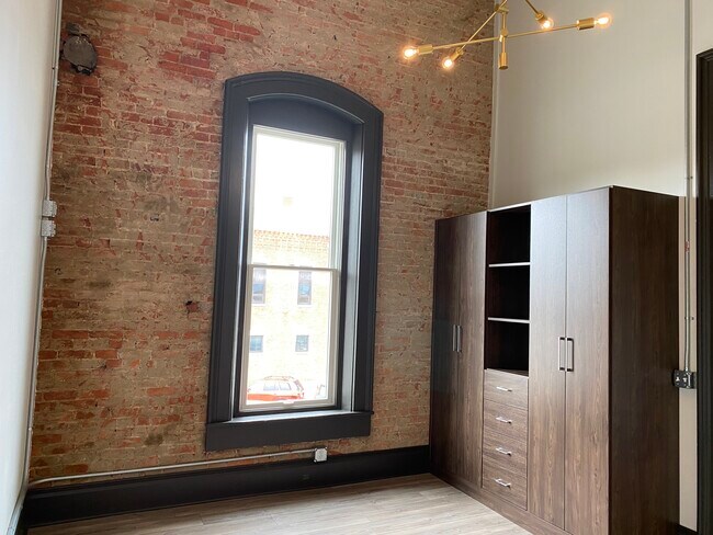 Dormitorio con armario a medida y pared de ladrillo. - 102 S Main St