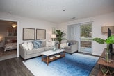 This single-floor residence offers a thoughtfully designed layout connecting the kitchen, dining, and living areas in an open, cohesive flow. The kitchen is outfitted with white cabinetry, granite-style countertops, stainless steel appliances including a range, microwave, and refrigerator, and wood-look flooring that extends into the dining area. The adjacent dining space accommodates a full table and is illuminated by a pendant light fixture. The living room features sliding glass doors that invite natural light and provide access to an outdoor area, complemented by additional windows and a textured ceiling.

The primary bedroom is generously sized, featuring plush carpeting, a ceiling fan, large windows with outdoor views, and direct access to an en-suite bathroom and additional storage. The second bedroom also offers carpeting and a ceiling fan. Both bathrooms share a consistent design aesthetic, featuring white vanity cabinetry, granite-style countertops, an oval undermount sink, and a tiled shower-tub combination. Wood-look flooring runs throughout the wet areas, adding warmth and durability. Neutral wall tones throughout the residence create a clean, cohesive ambiance.