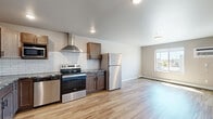 Located at 5652 36th Ave S in Fargo, ND, this one-bedroom, one-bathroom unit offers a practical and modern layout across a single floor. Light-toned hardwood flooring flows throughout the entire space, creating a cohesive and clean aesthetic.

The kitchen is a standout feature, boasting rich, medium-toned wood cabinetry with black hardware, granite countertops, and a classic white subway tile backsplash. A full suite of stainless steel appliances is included — refrigerator, electric range, dishwasher, built-in microwave, and a stainless steel wall-mounted range hood — providing a well-equipped cooking environment. Recessed lighting illuminates the kitchen, enhancing its functionality.

The bedroom is a comfortable, well-proportioned space finished in neutral tones. It features a large sliding double-door closet offering ample storage, along with an additional door for further access. A window allows natural light to brighten the room, complemented by a ceiling-mounted light fixture. A baseboard heater ensures warmth during Fargo's colder months.

The open layout of the main living area connects the kitchen and living spaces efficiently, making the most of the available square footage. The neutral gray and white wall palette throughout keeps the unit feeling bright and move-in ready.