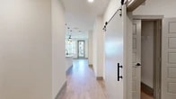 Located at 5400 Haltom Rd in Haltom City, TX, this thoughtfully designed 2-bedroom, 2-bathroom residence offers a clean, modern aesthetic across a single level. Light wood-tone flooring flows throughout the main living areas, complemented by crisp white walls and an abundance of natural light from well-placed windows.

The open-concept kitchen and living area serves as the heart of the home. The kitchen is equipped with stainless steel appliances, including a refrigerator, range, and dishwasher, alongside white shaker-style cabinetry and a granite-topped island with a deep single-basin sink and matte black fixtures. Pendant lighting adds a stylish, contemporary touch above the island.

A striking sliding barn door with matte black hardware connects spaces and adds a modern farmhouse character to the interior. The living area benefits from natural light and an open connection to the kitchen.

The primary bedroom is a comfortable, well-proportioned retreat featuring plush carpeting, a ceiling fan, and a window with outdoor views. The second bedroom is equally bright and functional.

Both bathrooms are finished with granite countertops and matte black fixtures. One features a tub-shower combination with large-format tile surround, while the other offers clean, minimal finishes. A dedicated closet provides additional storage. The overall ambiance is bright, clean, and move-in ready.