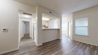 This thoughtfully designed 2-bedroom, 1-bathroom residence offers a practical and comfortable single-floor layout. The entry opens into a bright dining area accented by a chandelier and natural light from a window, with light wood-tone flooring that extends throughout the main living spaces. The galley-style kitchen is efficiently organized with wood-trimmed cabinetry, laminate countertops, a full suite of white appliances including a refrigerator and electric range, and a dishwasher. A peninsula counter separates the kitchen from the living and dining areas, creating an open, connected feel. The living area is spacious and airy, with a sliding door providing access to the outdoors and allowing additional natural light. Both bedrooms are carpeted and feature ceiling fans with light fixtures, generous wall space, and access to closets. The primary bedroom is notably spacious and includes a walk-in closet fitted with wire shelving for organized storage. The full bathroom is outfitted with a tub-shower combination with tile surround, a vanity with wood-trimmed cabinetry, and a mirrored medicine cabinet. A dedicated laundry area adds everyday convenience. The residence presents a neutral, move-in-ready palette throughout.