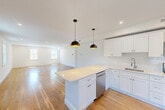 Located at 1 Pleasant St, Unit 201 in Cohasset, MA, this well-appointed 2-bedroom, 3-bathroom residence offers a thoughtfully designed single-floor layout with a clean, contemporary aesthetic. Warm hardwood floors flow consistently throughout the unit, complementing the bright, neutral palette that defines every room.

The open-concept kitchen and living area serves as the heart of the home. The kitchen is outfitted with crisp white shaker cabinetry, light stone countertops, a subway tile backsplash, stainless steel appliances, and a pendant light fixture, creating a functional yet stylish space. The adjoining living area benefits from abundant natural light through multiple double-hung windows.

The spacious primary bedroom includes an en-suite bathroom and generous closet space. The second bedroom also offers ample room, with double closet doors and access to natural light. All three bathrooms are finished with white vanities, stone countertops, and light-toned tile flooring, maintaining a cohesive and clean design language. One bathroom features a bright window overlooking the outdoors.

Additional spaces include a dedicated utility room, entrance foyer, hallway, and closet, providing practical storage and organization throughout. The overall ambiance is fresh, modern, and move-in ready.