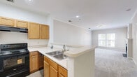 This one-bedroom residence at 9701 Summit Cir in Upper Marlboro, Maryland offers a well-organized single-floor layout designed for comfortable everyday living. The combined kitchen and living area forms the heart of the home. The kitchen is equipped with warm honey-toned wood cabinetry, light countertops, a double-basin stainless steel sink, and black appliances including a range with overhead ventilation and a full-size refrigerator. Light wood-look flooring runs throughout the kitchen, complementing the neutral color palette. The living room is carpeted and finished with elegant crown molding and a classic fireplace framed by a white mantel with a dark surround, serving as the room's focal point. Natural light filters in through windows that offer views of the surrounding community. The generously sized primary bedroom features plush carpeting, soft neutral walls, and a large window that brings in ample daylight. It provides direct access to a dedicated closet for ample storage. The in-unit laundry room houses a full-size side-by-side washer and dryer beneath wire shelving, adding everyday convenience. The space maintains a clean, neutral aesthetic throughout with consistent warm beige tones and white trim detailing.