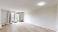 Located at 360 Falshire Drive NE in Calgary, AB, this well-appointed 3-bedroom unit offers a functional and comfortable single-floor layout. The open living area is finished with light wood laminate flooring that runs throughout, creating a bright and cohesive feel. Crisp white walls and neutral tones contribute to an airy, clean ambiance across all rooms.

The galley-style kitchen is thoughtfully updated with white cabinetry featuring black hardware accents, stone-look countertops, a classic white subway tile backsplash, and a stainless steel dishwasher. A range hood and track lighting provide practical illumination for meal preparation.

The spacious primary bedroom offers generous proportions and features a full-width mirrored sliding closet, maximizing both storage and the sense of space. The two additional bedrooms are similarly finished with light flooring and mirrored sliding closets, each benefiting from windows that frame outdoor greenery views and allow ample natural light to filter through.

Baseboard heating is present throughout the unit, ensuring efficient warmth during Calgary's colder months. The living area opens to a private balcony through a large sliding glass door, offering pleasant outdoor views of the surrounding neighbourhood. The textured ceilings in select rooms add subtle character to the overall design.
