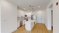 This thoughtfully designed 3-bedroom, 2-bathroom residence at 518 Vosseller Ave in Bound Brook, NJ offers a bright, modern living experience across a single floor. The open-concept kitchen and living area serves as the heart of the home, anchored by a sleek quartz-topped island beneath elegant brass pendant lights. The kitchen features white shaker cabinetry with gold hardware, a classic tile backsplash, stainless steel appliances including a gas range, dishwasher, microwave, and French door refrigerator. Light wood-tone flooring flows seamlessly throughout, complementing the crisp white walls and recessed lighting that keep the space feeling airy and bright. The spacious primary bedroom offers generous proportions with a well-organized walk-in closet featuring built-in shelving and hanging rods. Additional bedrooms include built-in closets and large windows with views of the surrounding neighborhood, filling each room with natural light. Two clean, modern bathrooms feature quartz vanity countertops, white cabinetry, and black-framed mirrors. A dedicated laundry room houses a full-size washer and dryer alongside the mechanical systems. The hallway connects all spaces efficiently, completing this well-appointed, move-in-ready residence.