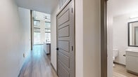 Located at 777 E 17th Ave in Denver's vibrant Capitol Hill neighborhood, this two-story loft showcases a striking modern industrial aesthetic across two thoughtfully designed levels. The main floor commands attention with dramatic soaring ceilings that amplify the sense of openness, clean white walls, and light hardwood flooring that runs throughout. The open-concept kitchen is equipped with stainless steel appliances, a gas range, built-in microwave, and crisp white cabinetry, anchored by a sleek white waterfall-edge island with an integrated sink and pendant lighting overhead. Exposed concrete columns add an authentic industrial character to the space. A sculptural spiral staircase with a bold black metal railing serves as both a functional and visual centerpiece, leading to the upper loft level. The upper floor offers a more intimate setting with plush carpeting, matte black open railings overlooking the main living area below, and a ceiling fan for added comfort. The bathroom is finished with classic white subway tile surrounding the soaking tub and shower, complemented by matte black fixtures, light wood-tone flooring, and a clean, minimalist vanity. A ceiling fan on the main level and abundant natural light from street-facing windows complete this well-appointed urban loft.