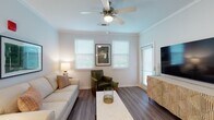 This single-floor residence offers a thoughtfully designed open-concept layout that seamlessly connects the kitchen, dining, and living areas. The kitchen is a standout feature, equipped with dark espresso shaker cabinets, stainless steel appliances including a refrigerator, range, and microwave, a mosaic tile backsplash, and a large granite-topped island with an undermount sink and bar seating — ideal for both meal preparation and casual dining. Pendant lighting above the island adds a refined touch, while recessed ceiling lights and crown molding elevate the overall aesthetic.

The living room is bright and welcoming, featuring dark hardwood-style flooring, a ceiling fan, crown molding, and multiple windows that allow generous natural light to fill the space. The bedrooms offer comfortable retreats; one features plush carpet, a ceiling fan, and a large window with outdoor views, while the other showcases a stylish accent wall. Both bathrooms are finished with granite countertops, dark wood vanity cabinetry, and wide mirrors. One bathroom includes a full tub-shower combo, while the other features a walk-in shower and access to a spacious walk-in closet. Consistent light-toned walls and quality finishes create a cohesive and modern ambiance throughout.