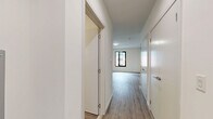 Located at 125 South Harrison Street in East Orange, NJ, this thoughtfully designed studio unit offers a clean, modern aesthetic with a practical and efficient layout. The space features wood-look plank flooring throughout, crisp white walls, and contemporary finishes that create a bright, cohesive feel.

The open-concept kitchen and living area serves as the heart of the unit. The kitchen is well-appointed with high-gloss white upper cabinetry, two-tone wood-finish lower cabinets, a white tile backsplash, light stone countertops, and a full suite of stainless steel appliances including a refrigerator, range, over-the-range microwave, and dishwasher. A wall-mounted mini-split HVAC unit ensures year-round climate control.

A dedicated bedroom area offers a tranquil retreat, featuring a black-framed window that brings in natural light and views of the surrounding neighborhood. The room is complemented by clean white walls and ample floor space.

The hallway connects the living areas to two closets, providing generous storage, and leads to the full bathroom. The bathroom is finished in a modern style with a white floating vanity, an illuminated mirrored medicine cabinet, and a soaking tub with a glass shower enclosure. The unit's efficient design maximizes every square foot, making it an ideal space for comfortable urban living.