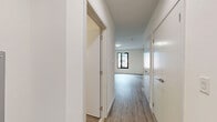 Located at 125 South Harrison Street in East Orange, NJ, this thoughtfully designed studio unit offers a clean, modern aesthetic with a practical and efficient layout. The space features wood-look plank flooring throughout, crisp white walls, and contemporary finishes that create a bright, cohesive feel.

The open-concept kitchen and living area serves as the heart of the unit. The kitchen is well-appointed with high-gloss white upper cabinetry, two-tone wood-finish lower cabinets, a white tile backsplash, light stone countertops, and a full suite of stainless steel appliances including a refrigerator, range, over-the-range microwave, and dishwasher. A wall-mounted mini-split HVAC unit ensures year-round climate control.

A dedicated bedroom area offers a tranquil retreat, featuring a black-framed window that brings in natural light and views of the surrounding neighborhood. The room is complemented by clean white walls and ample floor space.

The hallway connects the living areas to two closets, providing generous storage, and leads to the full bathroom. The bathroom is finished in a modern style with a white floating vanity, an illuminated mirrored medicine cabinet, and a soaking tub with a glass shower enclosure. The unit's efficient design maximizes every square foot, making it an ideal space for comfortable urban living.