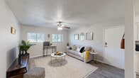 This efficiently designed 2-bedroom, 1-bathroom home makes excellent use of its single-floor layout. The living room serves as the heart of the space, featuring wood-look flooring, a ceiling fan with light fixture, and multiple windows fitted with blinds that allow abundant natural light. Neutral walls and a textured ceiling contribute to a clean, modern aesthetic throughout.

The kitchen is outfitted with white shaker-style cabinetry, light stone-look countertops, and a full suite of stainless steel appliances including a refrigerator, electric range, microwave, and dishwasher. A dedicated dining area adjacent to the kitchen and living room provides a functional space for meals.

The primary bedroom is a comfortable retreat, featuring a ceiling fan, a window with natural light, and wood-look flooring. It also includes a walk-in closet with dual hanging rods and hardwood-style flooring, offering generous storage. The second bedroom provides additional flexible living space.

The bathroom features a white vanity with marble-look countertop, a large mirror, and clean, bright finishes. A hallway connects the bedrooms and bathroom, completing the practical and straightforward floor plan. Throughout, consistent flooring and neutral tones create a cohesive, inviting atmosphere.