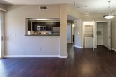 Located at 41965 Margarita Rd in Temecula, California, this single-floor residence offers a well-designed, open-concept layout with a cohesive blend of modern finishes and functional living spaces. Rich, dark hardwood flooring runs throughout the main living areas, lending warmth and a polished aesthetic to the entire unit.

The living area is bright and airy, anchored by a ceiling fan and sliding glass doors that open to a private balcony, filling the space with natural light and providing outdoor views. A pass-through counter connects the living area to the kitchen, which features dark cabinetry, granite-style countertops, stainless steel appliances including a refrigerator, range, and microwave, and a window that further enhances natural light. A stacked washer and dryer unit is conveniently integrated into the layout.

The bedroom is generously proportioned, finished with plush carpeting, a ceiling fan, and a large walk-in closet with built-in shelving. An en-suite bathroom offers a dark-cabinet vanity with a granite-topped counter, a tub-shower combination, and hardwood flooring. An additional carpeted room with a ceiling fan and outdoor-facing window provides flexibility as a second bedroom or office. The unit's neutral color palette and clean white trim create a cohesive, move-in-ready ambiance throughout.