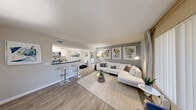 Located at 3580 E Alexander Rd in Las Vegas, NV, this 2-bedroom, 2-bathroom residence offers a thoughtfully designed single-floor layout that maximizes comfort and functionality. The open-concept living and dining area features wood-style flooring, neutral gray tones, and large windows that allow natural light to fill the space. A pass-through breakfast bar connects the living area seamlessly to the kitchen, which is outfitted with white cabinetry, dark stone-style countertops, stainless steel appliances including a gas range, refrigerator, and dishwasher, and light wood-style flooring. The primary bedroom features plush carpeting, a ceiling fan, a natural light-welcoming window with outdoor views, and a dedicated closet. The second bedroom is distinguished by a striking floor-to-ceiling accent wall with a bold blue stone-inspired mural. Both bathrooms are finished with white vanity cabinetry, dark stone-style countertops, and wood-style flooring. Each bathroom includes a well-lit vanity mirror and clean, neutral finishes. The overall aesthetic throughout the residence is modern and cohesive, with a soft, neutral color palette complemented by contemporary design details.