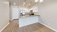 This single-floor unit offers a clean, contemporary design throughout, characterized by neutral warm tones, white trim, and consistent wood-look luxury vinyl plank flooring across the main living areas. The open-concept layout seamlessly connects the living room to the kitchen, creating an airy, cohesive space ideal for both daily living and entertaining. Recessed lighting illuminates the living area, which also benefits from a sliding door that invites natural light. The kitchen is a standout feature, showcasing crisp white shaker-style cabinetry, granite countertops, a peninsula with an undermount sink, and a full suite of stainless steel appliances including a French door refrigerator, electric range, and over-the-range microwave. Elegant pendant lighting above the peninsula adds a polished finishing touch. The bathroom continues the refined aesthetic with wood-look flooring, white cabinetry, granite countertops, a single undermount sink, and a full tub-shower combination. The bedroom offers plush carpeting underfoot and is complemented by a built-in closet with multiple shelving tiers and a hanging rod, providing well-organized storage. Throughout, the space maintains a bright, move-in-ready appearance with a cohesive, modern design sensibility.