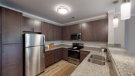 Located at 519 Carowill Dr in Greensboro, NC, this well-designed single-floor residence offers a cohesive blend of modern finishes and comfortable living spaces throughout. The kitchen is a standout feature, showcasing rich dark-espresso cabinetry, granite countertops, a classic subway tile backsplash, and a full suite of stainless steel appliances including a refrigerator, electric range, and built-in microwave. Wood-look flooring runs through the kitchen and connects seamlessly to the open living and dining areas, which are accented by crown molding and a ceiling fan. A peninsula counter provides casual seating and reinforces the open flow between the kitchen and living space. The living area offers generous wall space and natural light, creating a versatile and welcoming environment. The bedrooms feature plush carpeting, ceiling fans, and windows with blinds that allow for privacy and light control. The primary bathroom is spacious, equipped with a dual-sink granite vanity, dark cabinetry, a soaking tub, and direct access to a walk-in closet. A secondary bathroom includes a tub-shower combination with tiled surround and wood-look flooring. Throughout the residence, neutral tones and consistent finishes create a clean, modern aesthetic.