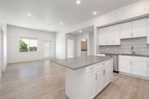 This well-appointed single-floor home in Chubbuck, Idaho offers four bedrooms and three bathrooms across a generously sized layout. The open-concept kitchen serves as a central highlight, featuring crisp white shaker cabinetry, a subway tile backsplash, dark countertops, a center island, and a full suite of stainless steel appliances including a refrigerator, range, and microwave. Recessed lighting and light hardwood-style flooring enhance the bright, clean aesthetic throughout the main living areas. A clean, well-lit hallway with white panel doors connects the rooms, providing an organized and efficient flow. The bedrooms offer a mix of hardwood-style and carpeted flooring, with several rooms featuring large windows that invite natural light and provide views of the surrounding neighborhood and greenery. The generously sized primary bedroom offers ample space for comfortable furnishing. The bathrooms are finished with white cabinetry, dark countertops, undermount sinks, large vanity mirrors with bar lighting, and glass-enclosed walk-in showers. The overall design is modern and clean, with a neutral color palette of whites and warm beiges that creates a fresh, move-in-ready atmosphere throughout.