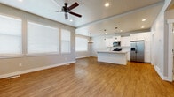 This well-designed three-floor home offers a thoughtful layout with modern finishes throughout. The main living area features an open-concept floor plan that seamlessly connects the living room and kitchen. Warm wood-look luxury vinyl plank flooring runs throughout the main level, complemented by neutral gray walls and abundant natural light streaming through large, white-shuttered windows. A ceiling fan anchors the living space, enhancing comfort year-round.

The kitchen is a standout feature, equipped with crisp white shaker-style cabinetry, a large center island with a white quartz countertop, stainless steel appliances including a gas range, microwave, and French door refrigerator, and stylish pendant lighting. A generously sized walk-in pantry with floor-to-ceiling built-in shelving provides exceptional storage.

A convenient powder room on the main level includes a pedestal sink and tile flooring. The upper floors host the bedrooms, which are carpeted for comfort and feature ceiling fans and bright windows. The primary bathroom is elegantly appointed with a double-sink vanity featuring white cabinetry and dark hardware, a frameless glass walk-in shower with floor-to-ceiling tile, and wood-look tile flooring. Additional bedrooms are well-sized and naturally lit, offering flexible living arrangements throughout this move-in-ready home.
