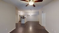 This single-floor residence offers a thoughtfully designed open-concept layout that seamlessly connects the living, dining, and kitchen areas. Rich dark hardwood-style flooring flows throughout the main living space, lending warmth and visual continuity to the open floor plan. The living area features vaulted ceilings with a ceiling fan and is generously sized, bathed in natural light and anchored by easy access to adjacent rooms.

The kitchen is a functional and stylish centerpiece, showcasing a breakfast bar peninsula with a light countertop, white cabinetry, a mosaic tile backsplash, stainless steel appliances including a refrigerator, range, and microwave, and a built-in sink. Track lighting overhead ensures the space is well-illuminated. A pendant light above the peninsula adds a decorative touch that bridges the kitchen and living areas.

The bedrooms are carpeted for comfort, with one featuring a walk-in closet and a window overlooking lush greenery outdoors. The textured ceilings carry through the bedroom spaces, adding a consistent design element throughout.

Two full bathrooms serve the residence. One includes a tub-shower combination with white tile surround, while the other offers a glass-enclosed walk-in shower, a wide vanity with a large mirror, and tile flooring. Both bathrooms are clean and efficiently laid out. Overall, the space presents a comfortable and practical living environment.