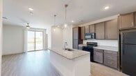 Located in Denton, TX, this thoughtfully designed 2-bedroom, 2-bathroom residence offers a comfortable and functional single-floor layout. The open-concept kitchen and living area serves as the heart of the home, featuring light wood-style flooring, granite countertops, a large center island with an undermount sink, rich dark-toned cabinetry, and black stainless appliances. Elegant pendant lighting illuminates the island, while recessed lighting brightens the space throughout. A sliding glass door leads to a private balcony, filling the living area with natural light. Both bedrooms are carpeted and offer a calm, neutral palette with ceiling fans and dedicated closets. The primary bedroom connects to a well-appointed en-suite bathroom featuring a dual-sink vanity with granite countertops and a walk-in shower, along with a generously sized walk-in closet equipped with wire shelving. The second bathroom includes a single vanity with granite countertops, dark cabinetry, and a full tub-shower combination. Additional conveniences include a dedicated laundry area and utility room. The space combines modern finishes with practical design, creating a clean, move-in-ready environment.