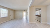 Located at 745 S Beach St in Daytona Beach, Florida, this single-floor residence offers 2 bedrooms and 3 bathrooms within a well-organized, efficiently laid-out floor plan. Light-toned ceramic tile flooring runs consistently throughout the home, contributing to a clean, cohesive aesthetic. Neutral beige walls and textured ceilings create a bright, airy atmosphere across all rooms.

The open living area flows naturally into an adjacent dining space, with ceiling fans providing comfort and a pass-through window connecting to the kitchen. The galley-style kitchen is well-appointed with white shaker cabinetry, granite-look countertops, stainless steel appliances including an electric range, dishwasher, and refrigerator, as well as a double stainless steel sink.

Both bedrooms are generously proportioned, each equipped with a ceiling fan and natural light from windows with blinds. The primary bedroom features dual windows that allow ample daylight. Two dedicated closets provide organized storage throughout the unit.

The three bathrooms maintain a consistent clean, white design, with one featuring a full tub-shower combination with tiled surround and a white vanity with lighted mirror. A central hallway connects the private areas of the home, enhancing the overall functional flow of the layout.