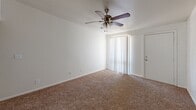 Located at 358 E Roeser Rd in Phoenix, AZ, this single-floor unit offers three bedrooms, one bathroom, a kitchen, and a hallway, making efficient use of its compact footprint. Each bedroom features wall-to-wall carpeting, a ceiling fan with light fixture, and a window dressed with vertical blinds that allows natural light to filter in. The primary bedroom is the most spacious of the three and includes a closet with built-in shelving and hanging rods. One of the bedrooms showcases a distinctive white-painted brick accent wall, adding a subtle architectural character to the space. The galley-style kitchen is fitted with warm wood-tone cabinetry, granite-look countertops, a stainless steel sink, and wood-look vinyl plank flooring. White appliances including a refrigerator and electric range complete the kitchen setup. A pantry or utility closet is accessible directly from the kitchen. The bathroom features a tub-shower combination with floor-to-ceiling warm-toned tile surround, chrome fixtures, a single vanity with sink, and a mirror. A window above the tub provides ventilation and natural light. The overall aesthetic is clean, neutral, and functional, well-suited for comfortable everyday living in the Phoenix area.