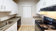 Located at 12350 Del Amo Blvd in Lakewood, California, this single-floor residence offers a clean, functional layout with a neutral color palette throughout. The living area is bright and open, featuring warm wood-style plank flooring and a sliding glass door fitted with vertical blinds that allows natural light to filter in while providing access to an outdoor patio. A ceiling fan adds comfort to the dining area, which connects seamlessly to the galley-style kitchen. The kitchen is well-appointed with white shaker cabinetry, dark countertops, light wood-style flooring, black appliances including an electric range and dishwasher, and a stainless steel refrigerator, all complemented by a window that brings in additional natural light. The bedrooms are carpeted and feature textured ceilings, neutral walls, and windows dressed with vertical blinds, creating comfortable and quiet retreats. One bedroom benefits from direct access to a full bathroom, which includes a single-sink vanity with dark countertops, white cabinetry, a tub-shower combination, and bright overhead lighting. A hallway connects the main living spaces, finished with the same wood-style flooring for a cohesive flow. The overall ambiance is clean, bright, and move-in ready.
