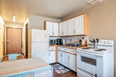 Located at 1935 Miller St in La Crosse, Wisconsin, this single-floor studio unit offers a practical and efficient layout across its compact footprint. An entry hallway with hardwood-style flooring leads into the main open-plan space, which seamlessly combines the kitchen, dining, and living areas. The kitchen is well-equipped with white cabinetry, wood-tone upper cabinets, a full-size refrigerator, an electric range, and a double sink — providing all essential cooking amenities in a thoughtfully arranged space. A ceiling fan overhead aids air circulation throughout the unit. The living and sleeping area occupies the far end of the space, bathed in natural light from a large sliding glass door framed by vertical blinds. A wall-mounted air conditioning unit ensures year-round comfort, complemented by baseboard heating. The bathroom, accessible from the entry corridor, features hardwood-style flooring, a white vanity with under-cabinet storage, a lighted mirror, and a bathtub/shower combination. A dedicated closet provides additional storage. The overall layout is straightforward and functional, making efficient use of every square foot for comfortable single-occupancy living.