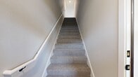 This well-appointed 3-bedroom, 2-bathroom townhome at 930 Terrapin Ln, Unit 202 spans 1,610 square feet across two floors. The ground floor (480 sq ft) includes an attached garage with an automatic opener, providing ample parking and additional storage space. The main living level (1,130 sq ft) features a modern kitchen outfitted with white shaker-style cabinetry, gray lower cabinets, white quartz countertops, stainless steel appliances including a refrigerator, range, microwave, and dishwasher, and light hardwood flooring. A large kitchen island with pendant lighting adds both functionality and style. The living area opens to a private balcony through sliding glass doors, offering outdoor views. Both bathrooms feature gray vanities with white countertops, hardwood-style flooring, and black matte hardware accents. The full bathroom includes a tub-shower combination. The spacious primary bedroom measures 370 square feet and features plush carpeting, a ceiling fan, and a barn door leading to the en suite bathroom. Two additional carpeted bedrooms also include ceiling fans. The home includes two closets and a staircase connecting both floors, completing this clean, contemporary residence.