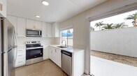 Located at 612 Los Arbolitos Blvd in Oceanside, California, this two-story residence offers a clean, modern aesthetic throughout. The interior is finished with light wood-look flooring and neutral warm-toned walls that create a bright, welcoming atmosphere across all rooms.

The kitchen is a standout feature, equipped with crisp white shaker cabinetry, light quartz countertops, and a full suite of stainless steel appliances including an electric range, over-the-range microwave, and dishwasher. A sliding glass door in the kitchen provides direct access to a private outdoor patio area, with views of palm trees lending a distinctly Southern California character to the space.

The living area is generously proportioned, featuring a ceiling fan with integrated lighting and an open sightline into the kitchen. Multiple bedrooms are spread across the two floors, each offering wood-look flooring, clean white baseboards, and a textured ceiling finish. Several bedrooms benefit from natural light through windows with exterior views of the surrounding neighborhood.

Additional rooms provide flexible use of space, with neutral finishes that allow for a variety of furnishing arrangements. Throughout the home, recessed lighting and consistent design choices contribute to a cohesive, move-in-ready environment well-suited for comfortable living in coastal Oceanside.