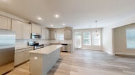 Located in Lawrenceville, GA, this well-appointed two-story home offers five bedrooms and four bathrooms across two thoughtfully designed floors. The main level features an open-concept layout connecting the kitchen, dining room, and living area, all finished with light wood-look flooring that lends a clean, modern aesthetic. The kitchen is a standout, boasting gray shaker-style cabinetry, granite countertops, a center island, stainless steel appliances, and recessed lighting. A glass-paned back door and large windows in the dining area flood the space with natural light and provide views of the surrounding greenery. The upper level houses the generous primary bedroom, distinguished by a tray ceiling, ceiling fan, plush carpeting, and a walk-in closet fitted with wire shelving. Additional bedrooms are well-sized and share access to well-appointed bathrooms, each with granite vanity tops and light wood-look flooring. A dedicated laundry room with utility connections adds everyday convenience. Hallways are bright and airy, featuring tall ceilings and white panel doors that maintain a cohesive, fresh look throughout. The home is designed with functionality and comfort in mind, making it an excellent fit for a variety of living needs.