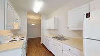 Located at 8230 Stobebrook Ter in Raleigh, NC, this single-floor residence offers a well-organized layout designed for comfortable everyday living. Rich, dark hardwood-style flooring runs throughout the main living areas and bedrooms, providing a warm and cohesive aesthetic.

The galley-style kitchen is efficiently designed with ample white cabinetry lining both walls, light-toned countertops, a double-basin stainless steel sink, a dishwasher, and a coil-top electric range. A pendant light fixture illuminates the passage leading into the dining area, creating a welcoming flow between spaces.

The living area is generously proportioned, featuring a ceiling fan, neutral walls, and a sliding glass door that opens to a balcony with outdoor views of surrounding greenery. An adjacent area provides additional flexible living space, complemented by a built-in storage closet.

The bedroom is bright and well-sized, with large windows framing lush tree views, tray ceiling detailing, and a reach-in closet with built-in shelving and hanging rods for organized storage.

The bathroom is finished with light tile flooring, a vanity with ample counter space and under-sink cabinetry, a large mirror, and a glass-enclosed shower stall. Throughout the home, a clean, neutral color palette and consistent finishes create a bright, move-in-ready environment.
