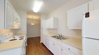 Located at 8230 Stobebrook Ter in Raleigh, NC, this single-floor residence offers a well-organized layout designed for comfortable everyday living. Rich, dark hardwood-style flooring runs throughout the main living areas and bedrooms, providing a warm and cohesive aesthetic.

The galley-style kitchen is efficiently designed with ample white cabinetry lining both walls, light-toned countertops, a double-basin stainless steel sink, a dishwasher, and a coil-top electric range. A pendant light fixture illuminates the passage leading into the dining area, creating a welcoming flow between spaces.

The living area is generously proportioned, featuring a ceiling fan, neutral walls, and a sliding glass door that opens to a balcony with outdoor views of surrounding greenery. An adjacent area provides additional flexible living space, complemented by a built-in storage closet.

The bedroom is bright and well-sized, with large windows framing lush tree views, tray ceiling detailing, and a reach-in closet with built-in shelving and hanging rods for organized storage.

The bathroom is finished with light tile flooring, a vanity with ample counter space and under-sink cabinetry, a large mirror, and a glass-enclosed shower stall. Throughout the home, a clean, neutral color palette and consistent finishes create a bright, move-in-ready environment.