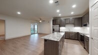This single-floor residence showcases a cohesive modern design with high-quality finishes carried throughout every room. The heart of the home is an open-concept kitchen and living area, where light hardwood-style flooring, recessed lighting, and a ceiling fan create a bright, welcoming atmosphere. The kitchen is a standout feature, equipped with dark espresso cabinetry, a classic white subway tile backsplash, stainless steel appliances — including a refrigerator with ice maker and a gas range with microwave — and a generously sized central island topped with striking granite countertops. The living area extends seamlessly toward a sliding glass door that opens to a private balcony, filling the space with natural light and outdoor views. The bedrooms offer plush carpeting, ceiling fans, and windows with views to the exterior, providing a comfortable and restful retreat. The bathrooms are elegantly appointed with dark wood vanities, granite countertops, and white tile detailing. The primary bathroom features a glass-enclosed walk-in shower, while a secondary bathroom offers a full tub-shower combination. A third half-bath provides additional convenience. Together, these spaces deliver a polished, move-in-ready living environment with thoughtful attention to detail.