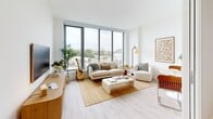Located at 1 Florida Ave NE in Washington, DC's NoMa neighborhood, this modern one-bedroom, one-bathroom residence is thoughtfully designed to maximize both comfort and functionality. The open-concept living and dining area serves as the heart of the unit, anchored by dramatic floor-to-ceiling windows that frame sweeping views of the Washington skyline and surrounding cityscape, flooding the space with abundant natural light. Light wood-toned flooring runs throughout, complementing the clean white walls and creating a warm, contemporary aesthetic. The combined living and dining area offers ample room for both relaxing and entertaining. The well-appointed kitchen features sleek white cabinetry and modern appliances, positioned conveniently adjacent to the main living area. The bedroom is a serene retreat with a built-in closet and soft, neutral finishes. A second closet provides additional storage. The full bathroom is finished with distinctive grey hexagonal floor tiles, a soaking tub with tiled surround, a wood-accented vanity, and a backlit mirror. An in-unit laundry area adds everyday convenience. With its modern finishes, striking city views, and efficient layout, this residence offers a refined urban living experience in one of DC's most dynamic neighborhoods.