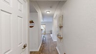 This well-appointed one-bedroom, one-bathroom home in Leesburg, Florida offers a thoughtfully designed single-floor layout that maximizes every square foot. The living room serves as the heart of the home, featuring wood-look flooring, a ceiling fan, and a sliding glass door that floods the space with natural light while providing direct access to an outdoor patio area. Adjacent to the living room, the dining area is defined by a stylish chandelier overhead and a window dressed in warm, layered curtains, creating an inviting setting for meals. The galley-style kitchen is efficiently arranged with light wood cabinetry, ample counter space, a full suite of appliances including a gas range, microwave, and refrigerator, and wood-look flooring that ties seamlessly into the main living areas. A dedicated in-unit laundry room accommodates a full-size washer and dryer with overhead shelving for added storage. The spacious primary bedroom features plush carpet, a ceiling fan, and a bright window with sheer curtains that allow soft natural light to fill the room. The full bathroom is finished with wood-look flooring, a combined tub and shower, a vanity with light stone countertops, and light wood cabinetry. Neutral tones and clean lines throughout give this home a warm, cohesive feel.