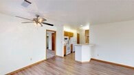 Located at 50 E Fieldstone Cir in Oak Creek, Wisconsin, this single-floor residence offers a well-organized layout designed for comfortable everyday living. The open living area is finished with light hardwood-style flooring and includes a ceiling fan, creating a bright and airy atmosphere. A built-in shelving unit with recessed lighting serves as a practical focal point, offering generous storage and display space.

The kitchen is thoughtfully appointed with warm honey-toned cabinetry, light countertops, a double-basin sink, and white appliances including a refrigerator, range, microwave, and dishwasher. A peninsula counter extends into the living area, providing additional workspace and a natural transition between the kitchen and main living space.

The bedrooms feature plush carpeting and natural light from large windows with views of the surrounding neighborhood. One bedroom includes a spacious walk-in closet with dual clothing rods and shelving, while another features sliding wood-panel closet doors for ample storage.

Two full bathrooms serve the residence. One features a tub-shower combination with a single-sink vanity, while the other offers a sleek sliding glass shower enclosure, tile flooring, and a well-lit vanity mirror. Warm wood trim and neutral tones throughout the space contribute to a cohesive and welcoming aesthetic.