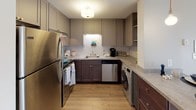 This renovated two-bedroom, one-bathroom Cascade unit is laid out on a single floor, offering a thoughtfully updated interior with contemporary finishes throughout. The open-concept living and dining area features light luxury vinyl plank flooring and a ceiling fan, creating a bright, airy atmosphere. A sliding glass door leads to a private balcony overlooking a tree-lined exterior, allowing natural light to fill the space.

The kitchen is well-appointed with two-tone cabinetry — taupe uppers and dark lower cabinets — paired with a classic subway tile backsplash, light stone-finish countertops, and stainless steel appliances including a refrigerator, range, and dishwasher. A peninsula with bar seating connects the kitchen to the living area. In-unit laundry is conveniently integrated within the kitchen space.

Both bedrooms feature plush carpeting and neutral tones. The primary bedroom includes a dedicated closet, while the second bedroom benefits from large windows that invite natural light. The full bathroom offers a tub-shower combination with a dark-cabineted vanity and wood-look flooring, completing this move-in-ready home.