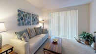 This single-floor residence offers a cohesive coastal-inspired design throughout, with a warm and inviting atmosphere that carries from room to room. The living area features plush carpeting and a large sliding glass door dressed with vertical blinds, allowing for generous natural light. Adjacent to the living space, the dining area accommodates a full dining set beneath a decorative pendant light, with a bi-fold closet nearby adding practical storage.

The galley-style kitchen is outfitted with white cabinetry, white appliances including an electric range and refrigerator, and durable wood-look flooring that extends into the adjoining spaces. A dedicated in-unit laundry area houses a full-sized washer and dryer with overhead wire shelving for added convenience.

The bedrooms carry a relaxed, nautical charm, each featuring ceiling fans, carpet flooring, and exposed beam-style ceiling details. Vertical blinds on the windows allow natural light to filter in while maintaining privacy. The bathrooms are finished in clean white tile and cabinetry, with one offering a tub-shower combination and another featuring a long vanity countertop with ample storage. The overall design is light, airy, and consistently styled with beachy accents throughout.