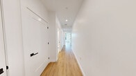 Located on the fourth floor at 199 Gardner Street in Boston's West Roxbury neighborhood, Unit 407 is a thoughtfully designed one-bedroom, one-bathroom residence offering a clean, contemporary aesthetic throughout. Light-toned hardwood-style flooring and crisp white walls run throughout the unit, creating a bright and cohesive atmosphere.

The open-concept kitchen and living area serves as the heart of the home. The kitchen features warm wood cabinetry with black hardware, a sleek grey countertop island with an undermount sink, stainless steel appliances including a refrigerator and range, and stylish globe pendant lighting. Large black-framed windows flood the space with natural light and frame lush tree canopy views.

The living area is generously proportioned, with additional black-framed windows overlooking the surrounding greenery, providing a calm and airy setting. The bedroom offers two windows with tree views and roller shades, maintaining a peaceful, nature-connected ambiance.

The bathroom is finished in a modern style, featuring large-format white wall tile, a frameless glass walk-in shower with black fixtures, and a wood-toned vanity with a white countertop. The private balcony extends the living space outdoors, offering views of the landscaped community grounds and surrounding tree canopy.