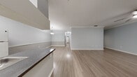 Located in Tampa, FL, this single-floor residence offers a thoughtfully designed layout that balances open communal spaces with comfortable private areas. The open-concept living and dining area is finished with light wood-look flooring, soft gray walls, crown molding, and a ceiling fan, creating a bright and airy atmosphere. Large vertical blinds allow natural light to filter in, enhancing the sense of space throughout.

The kitchen is well-appointed with white cabinetry, dark granite-style countertops, a stainless steel double sink, a tile backsplash, and white appliances including an electric range and full-size refrigerator. A peninsula with a bold overhead vent hood adds a functional focal point, seamlessly connecting the kitchen to the main living area.

The bedrooms feature plush carpeting, ceiling fans, and closets with built-in shelving and hanging rods, providing generous storage. The primary bathroom is equipped with both a soaking tub and a separate glass-enclosed walk-in shower, complemented by a vanity with matching dark countertops and white cabinetry.

A dedicated in-unit laundry room accommodates a full-size washer and dryer with additional wire shelving overhead. The consistent light gray palette and wood-look flooring throughout the common areas tie the home together in a clean, modern aesthetic.