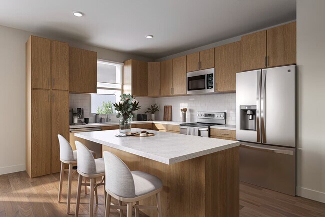 Cocina moderna con armarios de madera, electrodomésticos de acero inoxidable y una gran isla. - Trail House Apartments