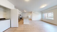 Located at 10602 Burns Rd in Pasco, WA, this thoughtfully designed 2-bedroom, 2-bathroom residence offers a clean, contemporary aesthetic across a single floor. The open-concept kitchen and living area serves as the heart of the home, featuring light wood-style flooring, crisp white walls, and abundant natural light from large windows and a glass door that opens to the outdoors. The kitchen is well-appointed with stainless steel appliances — including a refrigerator, microwave, and range — complemented by light wood cabinetry, a neutral-toned countertop, and a spacious kitchen island with an integrated sink, ideal for both cooking and casual dining. A wall-mounted mini-split system provides efficient climate control throughout the main living area. Both bedrooms are carpeted for comfort and include windows with exterior views of the surrounding community. The primary bedroom features a walk-in closet outfitted with wire shelving, offering generous storage. The bathrooms are finished with wood-toned vanities, integrated sinks, and full tub-shower combinations set on matching wood-style flooring. A dedicated closet space accommodates in-unit laundry. The overall design is modern and neutral, creating a bright, functional living environment.