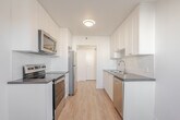 Located at 210 Fifth Ave in Kitchener, Ontario, Unit 203 is a thoughtfully designed suite offering a comfortable and functional layout across a single floor. The interior is finished with light-toned laminate hardwood flooring throughout, crisp white walls, and baseboard heating, creating a clean and cohesive aesthetic.

The galley-style kitchen is a standout feature, equipped with stainless steel appliances including a refrigerator, electric range, and over-the-range microwave. White shaker cabinetry lines both sides of the kitchen, complemented by dark countertops and a white subway tile backsplash, delivering a modern yet timeless look.

The two versatile rooms are bright and open, each benefiting from natural light streaming through windows. One room features a sliding closet door, providing practical storage. The living area offers generous open space with a passthrough to the hallway.

The bathroom is finished with classic white subway tile surrounding a full soaker tub, maintaining the unit's clean, contemporary style.

A private balcony extends the living space outdoors, offering views of the surrounding neighbourhood and ample open sky. The entry hallway provides a practical transition into the unit. Overall, this suite presents a fresh, move-in ready environment in a well-established Kitchener neighbourhood.